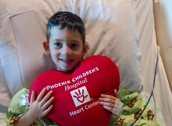 Oliver holding Phoenix Children's heart shaped pillow