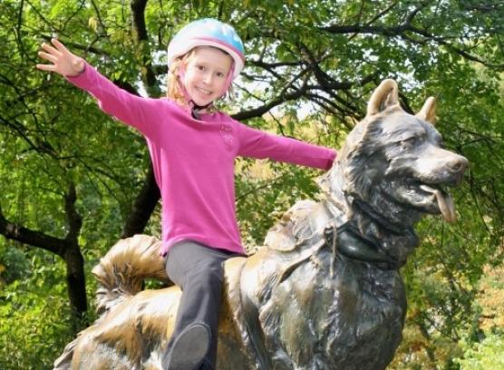 child sitting on top of dog statue