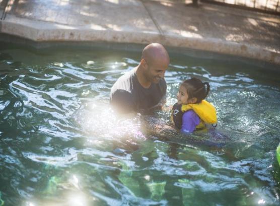 Man and child in life vest swimming in pool.
