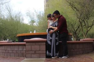 Father, mother and young child embracing, looking at pregnant belly