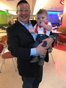 Provider holding infant wearing red suspenders