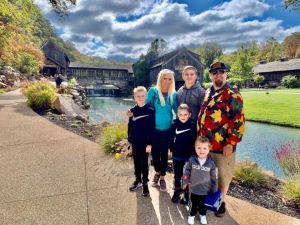 Family of 6 smiling in front of barn