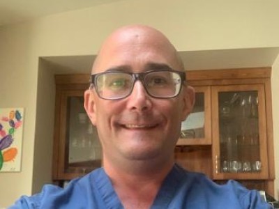Selfie of doctor in blue scrubs and glasses