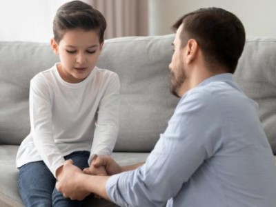 Father and son holding hands, sitting on couch
