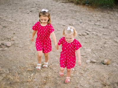 Two young girls holding hands outside