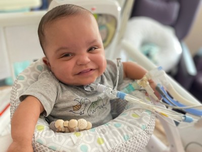 Baby in play seat, smiling at camera