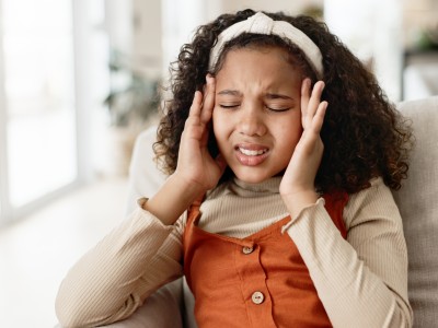 Adolescent girl pressing her temples in pain