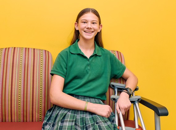 Girl sitting on a chair smiling with crutches